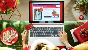 open laptop with Christmas scene and person purchasing online